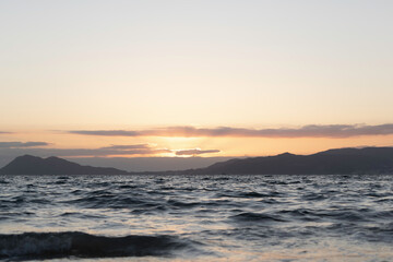 Fototapeta premium A summer sunset at sea with mountains in the background.