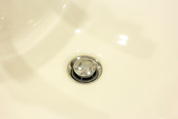 Drain hole in a white tub. Bathroom.