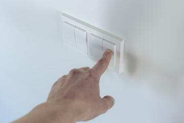 Hand presses a light switch with a finger