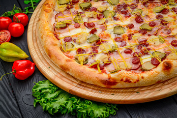 Delicious and fresh pizza with ham, sausage and pickled cucumbers