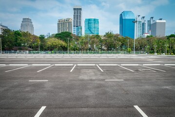 Empty space large outdoor asphalt car parking lot in city with city building background. Transport...