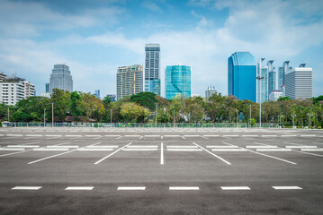 Empty space large outdoor asphalt car parking lot in city with city building background. Transport concept