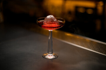 selective focus of beautiful wine glass with ice and cocktail on bar