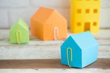 Fototapeta premium Colorful paper house on wooden table background with free copy space. Home loan, mortgage, real estate property or construction concept.