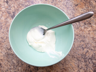 Spoon in white sour cream in a plate.