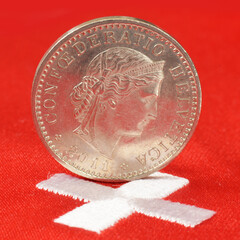 Swiss currency coins of franc on red flag with white cross