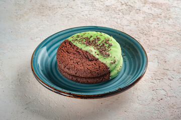 Chocolate oatmeal cookies covered with mint glaze and cocoa slices. Homemade cookies on a blue plate