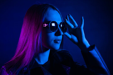 Cute girl with long hair near glowing pink neon city at night. Dyed blue pink hair of a young...