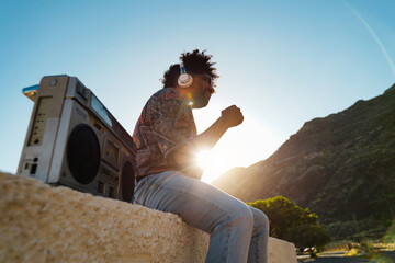 African american man listening music with vintage boombox stereo outdoor - Focus on headphones - obrazy, fototapety, plakaty
