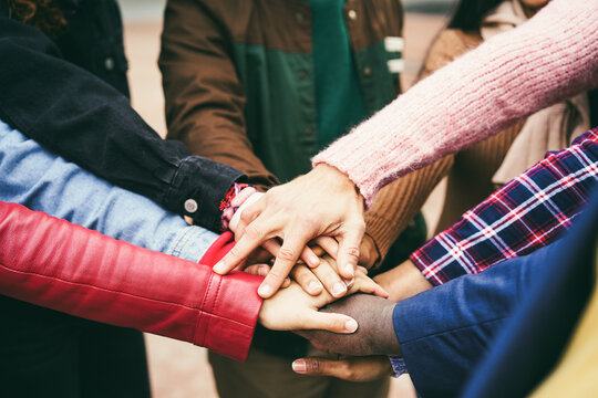 Young group of people stacking hands outdoor - Focus on hands
