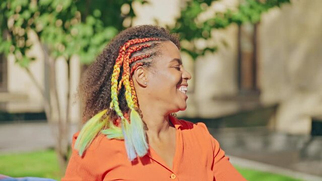 Joyful curly-haired black woman waving rainbow flag during lgbt pride parade