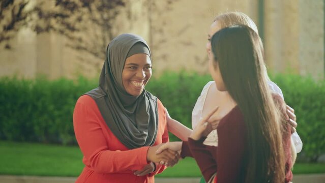Happy blond female introducing her multiethnic friends, women shaking hands