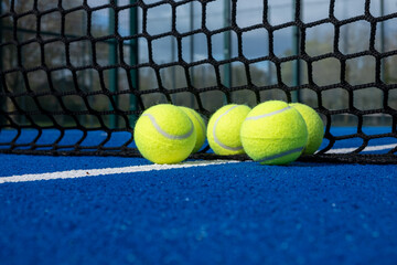 selective focus, five balls near the net of a blue paddle tennis court