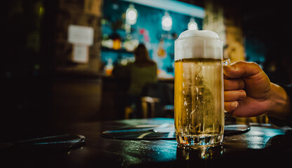 man hold a glass of beer in his hand at the bar or pub