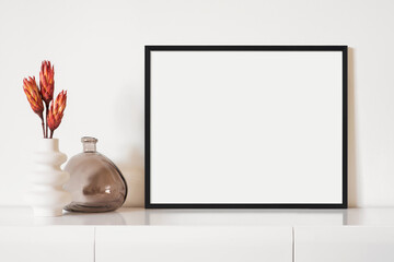 Empty horizontal frame mockup in modern minimalist interior with plant in trendy vase on white wall...