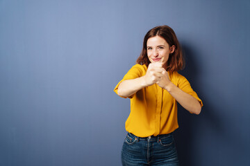 young business woman raises her fists for fun in front of blue background