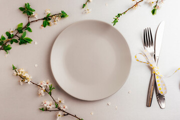 Spring table setting with gray plate and cherry blossom on silver background. Top view, flat lay. Space for text
