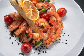 Fried shrimp in tomato sauce with lemon and tomatoes