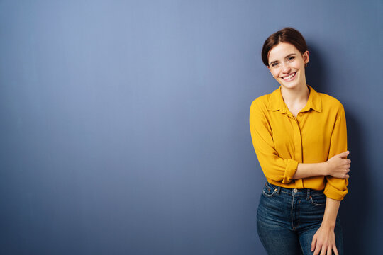 young relaxed business woman with yellow blouse stands in front of blue background