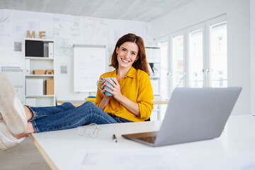 young modern business woman taking a break in the office and holding a cup in her hand - 495080703