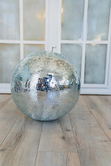 Mirrored disco ball on the floor in the room. elements of decor in retro style. accessories for...