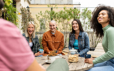 group of young people of generation z on the terrace of youth hostel having breakfast, group of travelers meeting people of different cultures, focus on the bald woman smile - Powered by Adobe