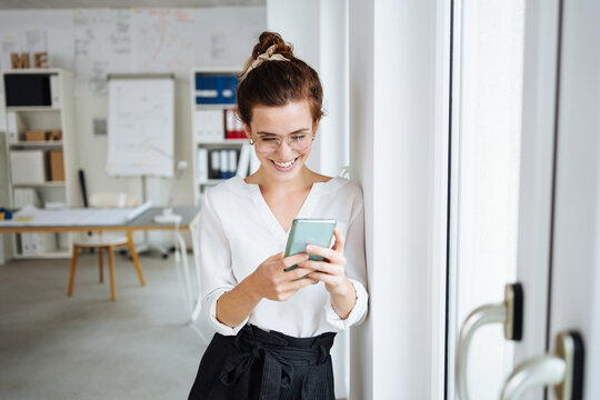 young modern business woman looking happily at her cell phone