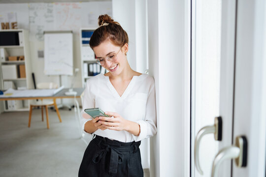 young modern business woman looking happily at her cell phone