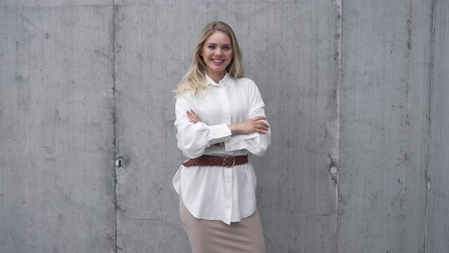 Confident young woman standing near shabby wall and looking at camera