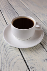 a cup of coffee on a white wooden background