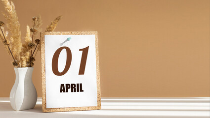 April 1. 1th day of month, calendar date.White vase with dead wood next to cork board with numbers. White-beige background with striped shadow. Concept of day of year, time planner, spring month