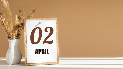 April 2. 2th day of month, calendar date.White vase with dead wood next to cork board with numbers. White-beige background with striped shadow. Concept of day of year, time planner, spring month