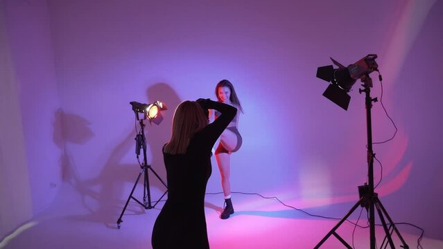 Woman photographer making portraits  in photo studio. Work of a photographer Backstage neon light