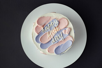 Bento cake with blue and pink cream cheese frosting and Happy birthday text on top. Birthday cake on a gray background. Asian small cake trend.