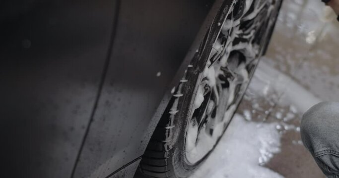 Car wash and detailing: detailer washes car's rims by foamy brush, 4k 60p Prores