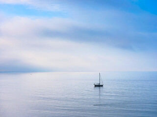 Lone Sailboat on a Misty Morning