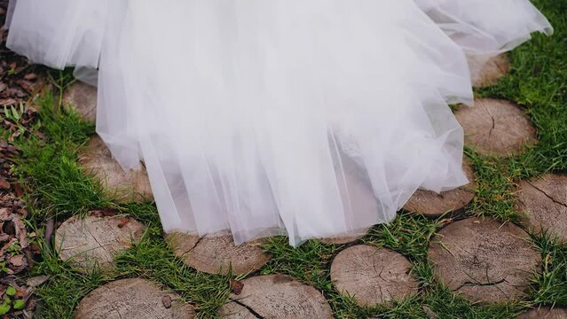 The hem of the white dress slides on the log pavement. The camera takes a close-up of the dress