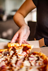 woman Hand takes a slice of chicken Pizza in paper box in cafe