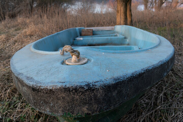 Fototapeta premium Rope knot on bow of old boat with cracked blue paint ashore in selective focus