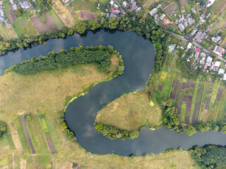 Aerial view of cottages in green forest by the blue lake in rural summer