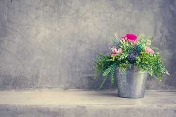 Beautiful artificial flower bouquet in the zinc pot with wall concrete background copy space.