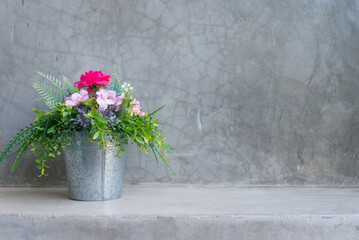 Beautiful artificial flower bouquet in the zinc pot with wall concrete background copy space.
