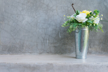 Beautiful artificial flower bouquet in the zinc pot with wall concrete background copy space.