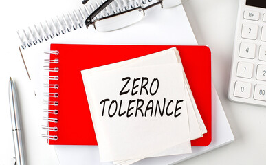ZERO TOLERANCE word on the sticker on notepad with pen and calculator