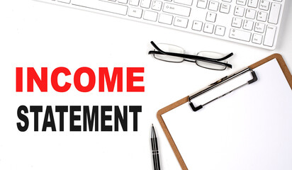 INCOME STATEMENT text written on the white background with keyboard, paper sheet and pen