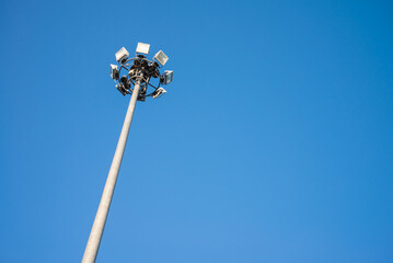 Tall outdoor spotlight stadium in day time with clear blue sky with copy space.