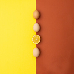 Easter eggs and lemon half in a line on yellow and orange background. Aesthetic minimal Easter concept. Flat lay. Copy space. 