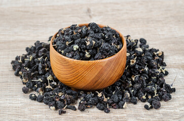 Black wolfberries or black goji berries, in a wooden bowl.