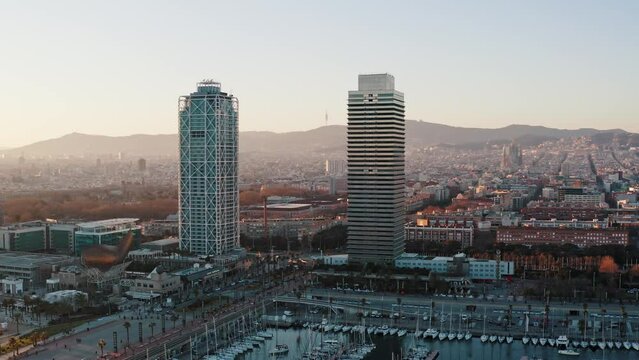Aerial panorama of coastal district in modern Barcelona. Wide shot of skyscrapers twins Hotel Arts and Torre Mapfre, Peix Fish sculpture located before luxury harbor for sailing yachts in Port Olimpic