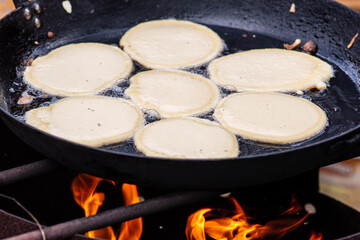 Blini, blin or blynai, pancakes traditionally made from wheat or buckwheat flour and served with smetana, tvorog, butter, caviar and other garnishes, preparing outdoor on an open fire